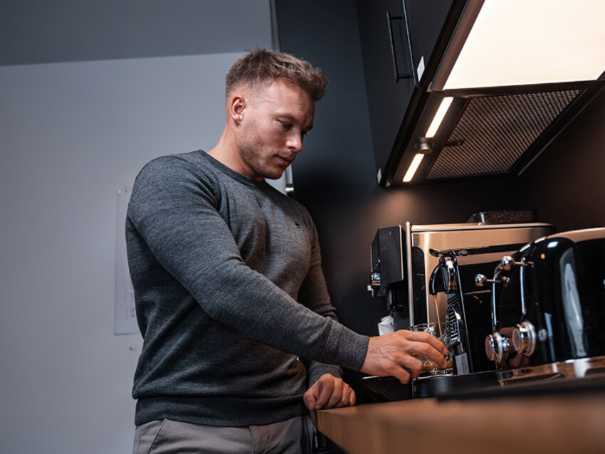 Mitarbeiter an der Kaffeemaschine in der Büroküche